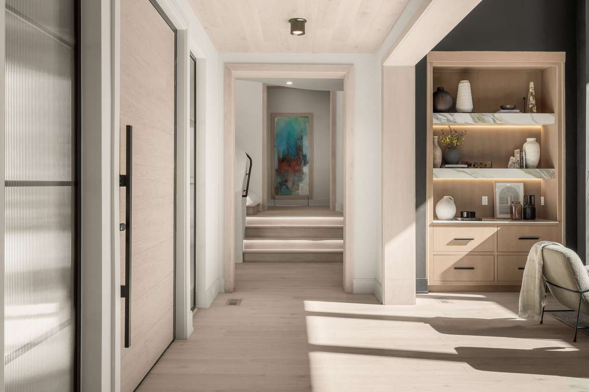 The biometric lock on the pivot door opens to the foyer with clean architectural lines and layered finishes that set a refined tone.