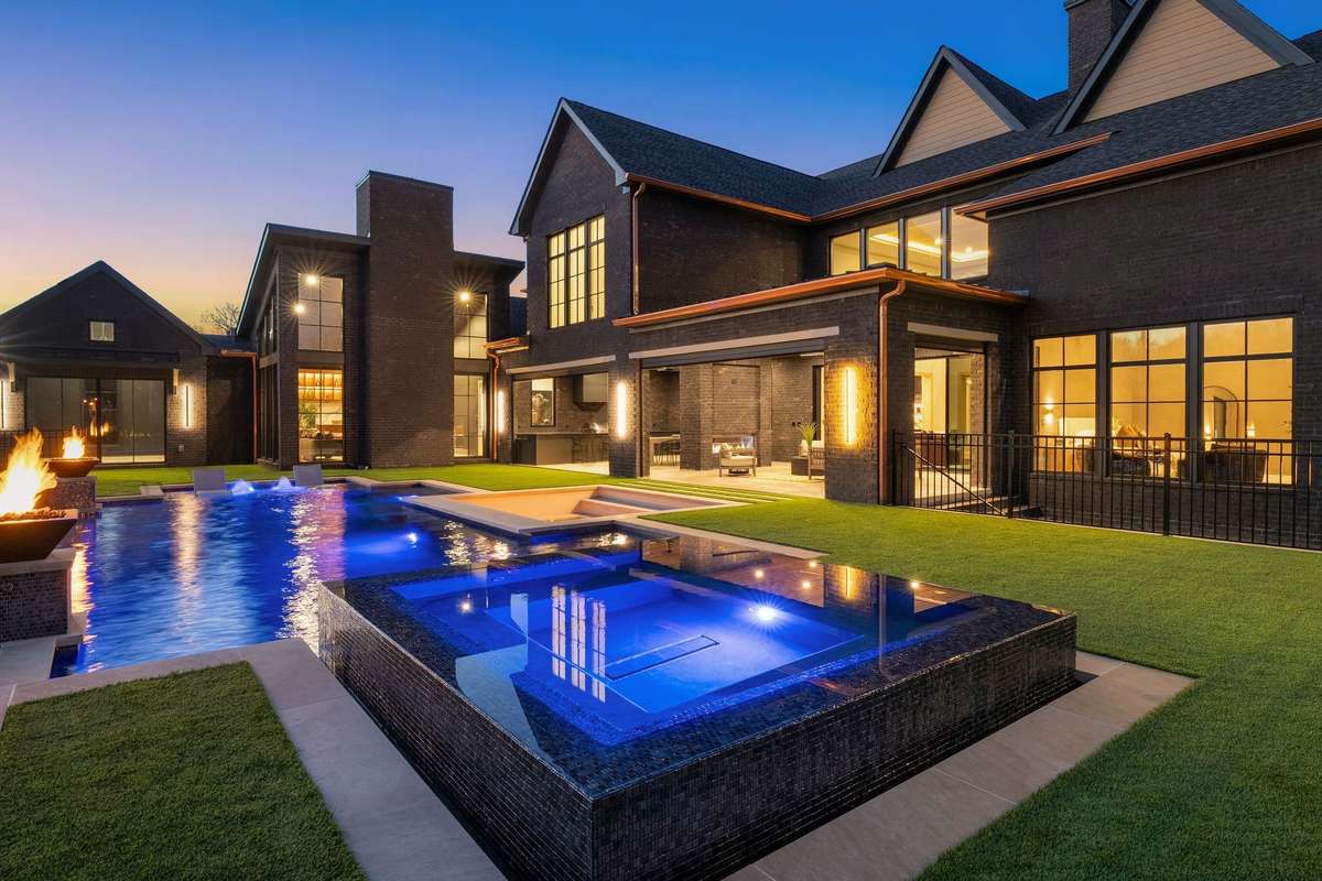 The gunite infinity pool features fire bowls, a tanning ledge and bar stools. Heated spa and expansive outdoor living areas create a private setting designed for every season.