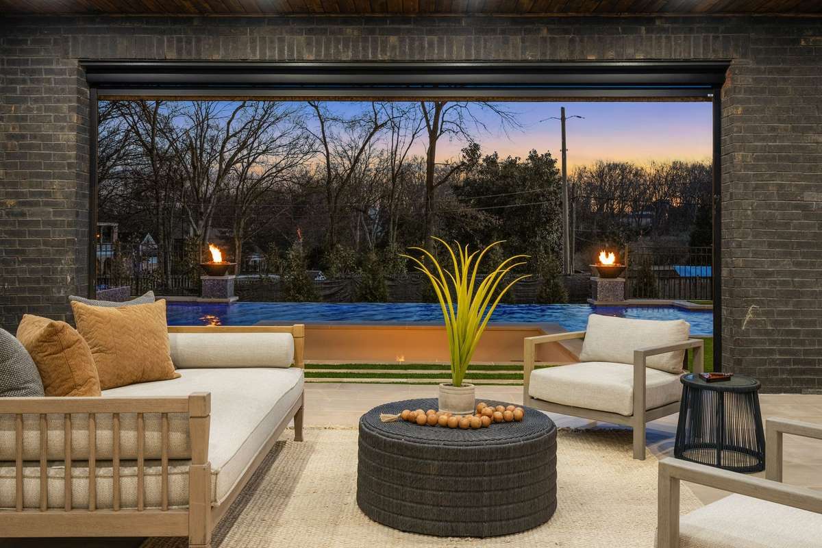 Just outside the living room you find a covered patio with motorized screens overlooking the pool and glowing fire elements—designed for relaxed evenings and open-air gathering.