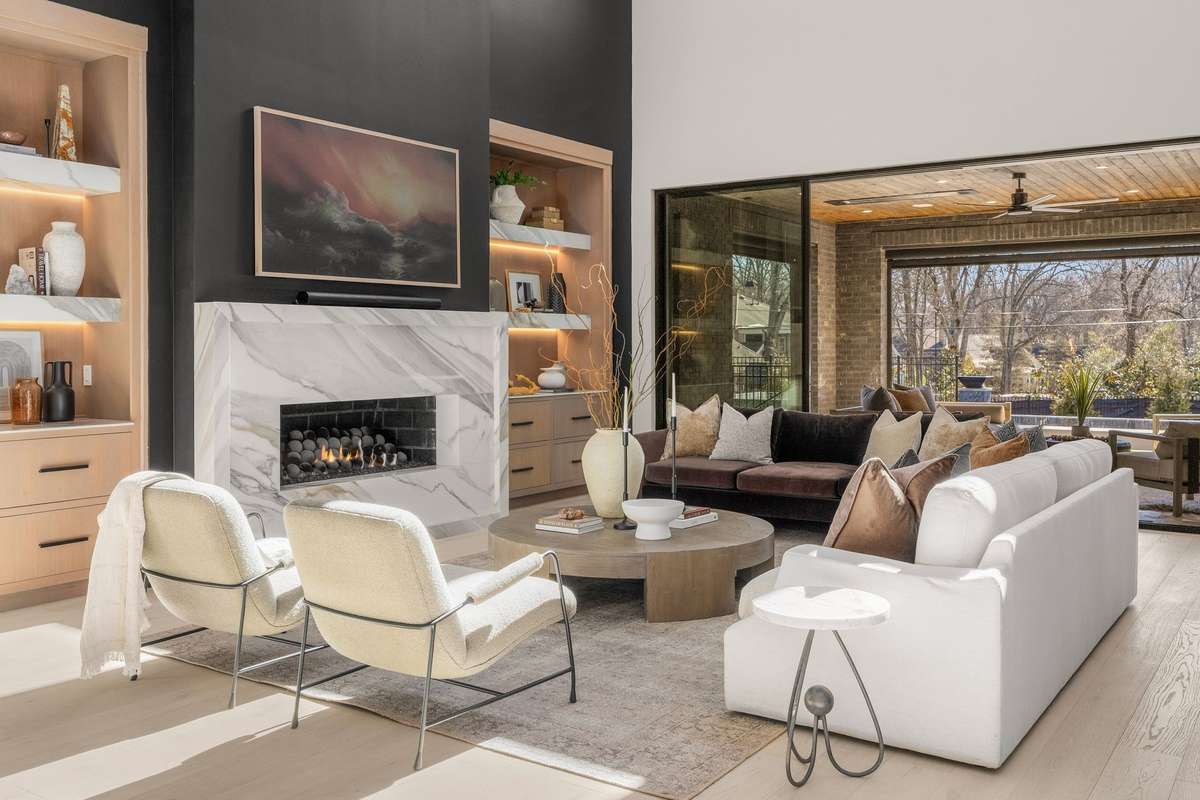 Marble with natural movement surrounds the fireplace, adding depth and artistry to the gathering space. Notice the accent lighting on the shelves. No detail spared.