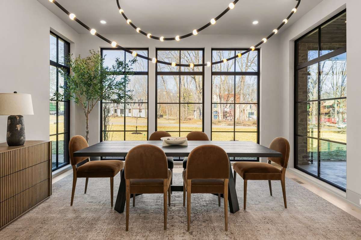 Wrapped in windows on three sides, the dining room captures serene garden views beneath sculptural lighting.