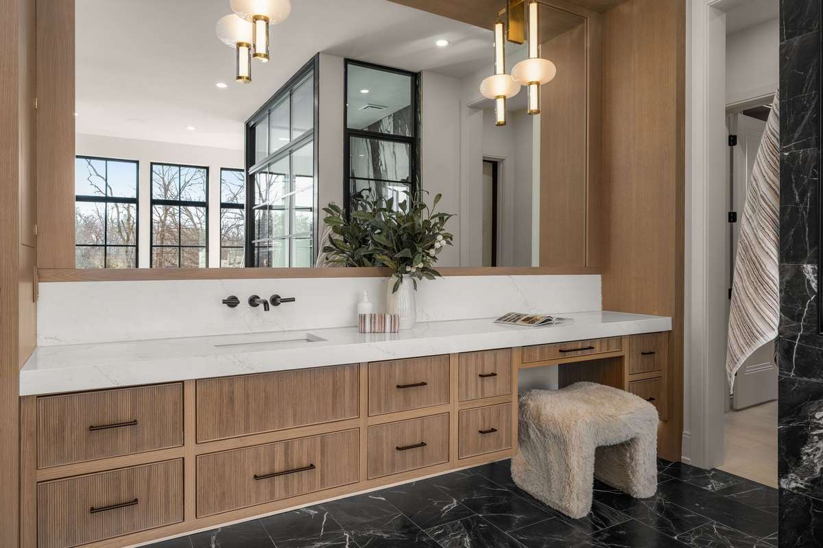 Her vanity features a thoughtfully designed makeup nook, adding a layer of personalization to the elevated primary bath.