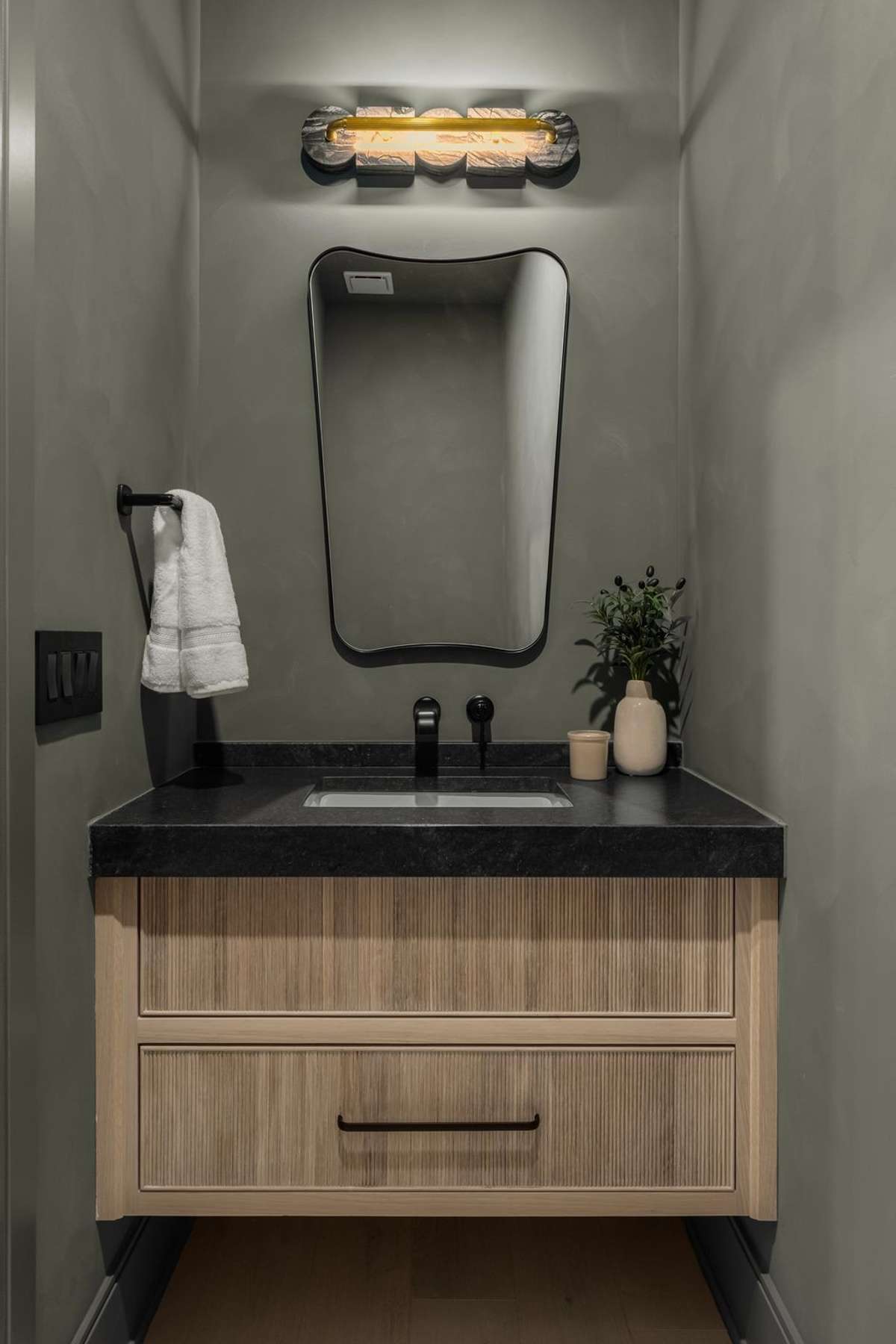 Moody and refined, this lime washed designer powder bath pairs rich tones with sculptural lighting—an elevated statement in even the smallest details.
