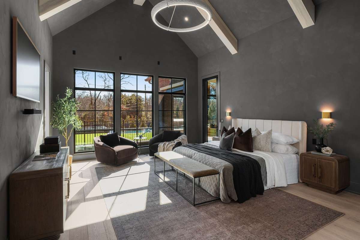 A true private retreat, the serene primary suite on the main level of the home features vaulted ceilings with beams, expansive windows, and tranquil views designed to feel both grand and calming.