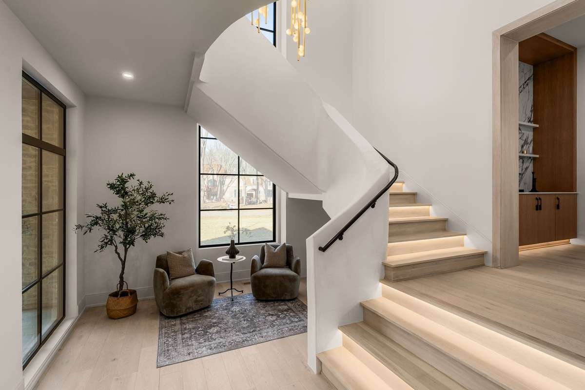 The Arcustone sculptural staircase is designed as both art and architecture—featuring soft, curved lines, integrated lighting, and a serene sitting area framed by oversized windows.