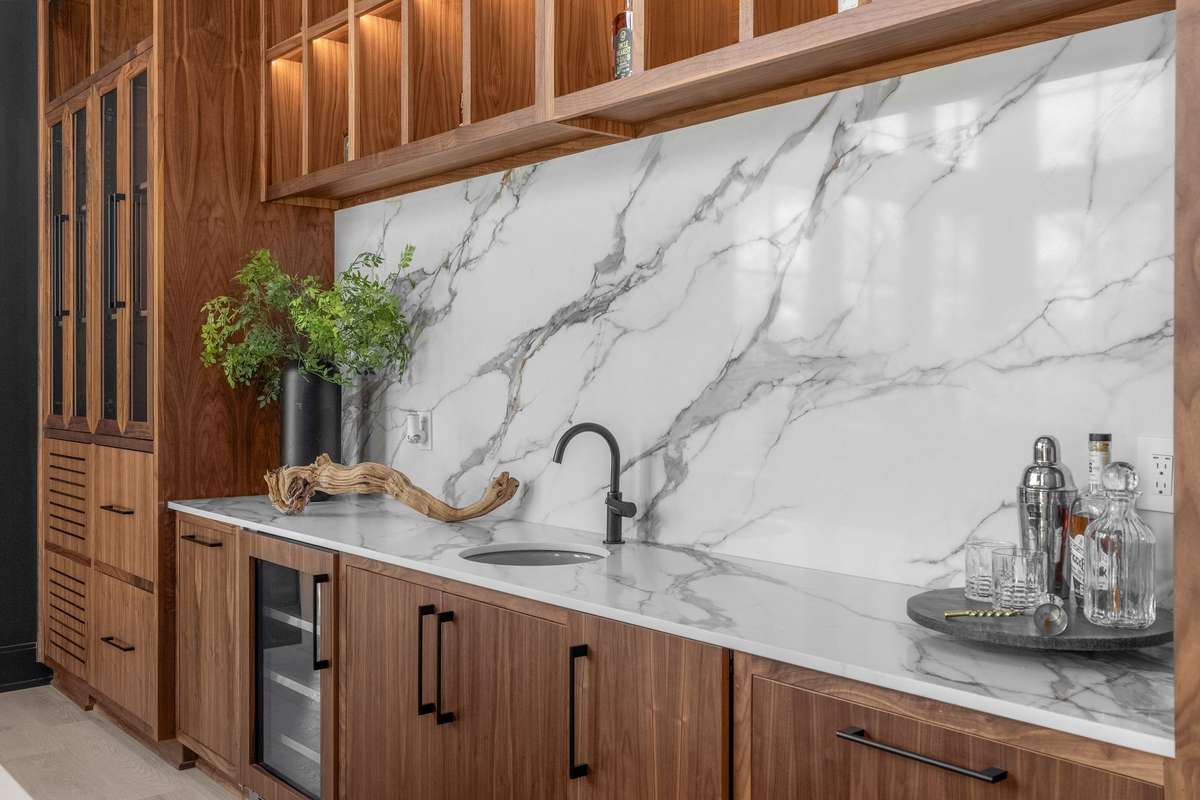 Marble and custom cabinetry combine to form a beautifully detailed entertaining space with a prep sink, beverage refrigerator and ice maker.
