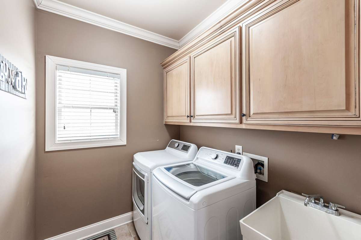 Located on the main level, the utility room offers ample storage space and a soaking sink, combining function and convenience for everyday living.