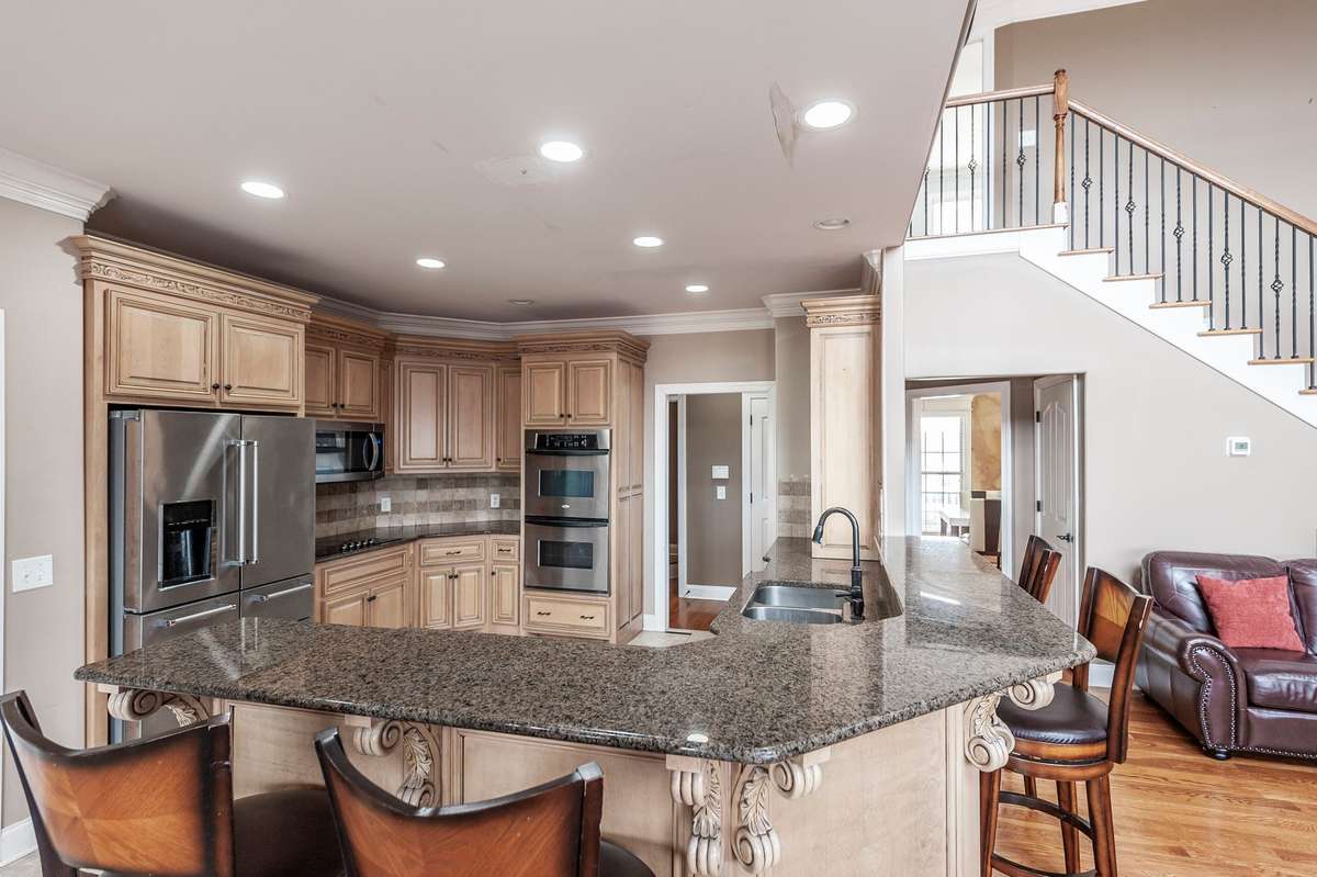 The kitchen is appointed with extensive cabinetry, granite countertops, double ovens, and stainless-steel appliances.