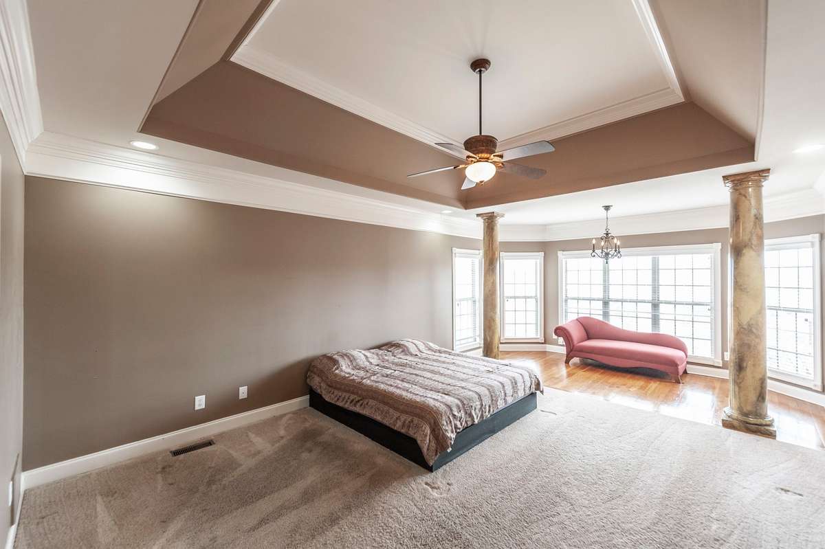 The first-floor primary suite serves as a tranquil retreat, highlighted by a tray ceiling and a dedicated sitting area for relaxation.