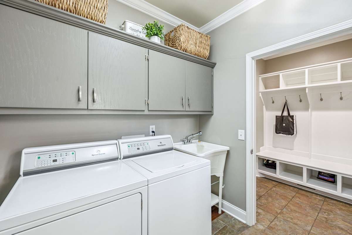 The Utility Room has a sink, cabinets and beautiful stained wood table for folding clothes