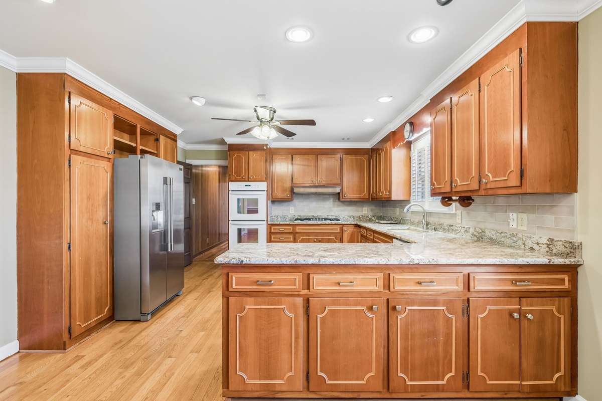 Lots of cabinetry, 2 pantries, double oven, gas cooktop, granite, & tile backsplash