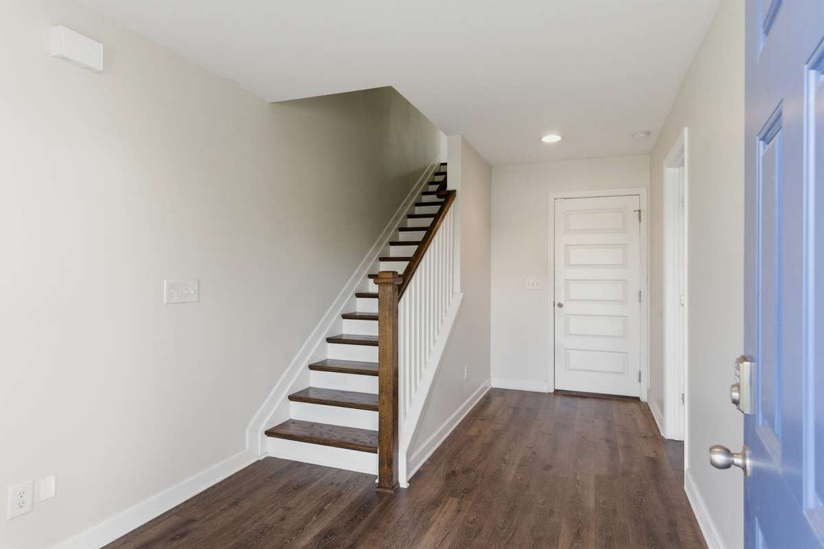 Welcoming entry with hardwood floors and a clean-lined staircase leading to the upper level.