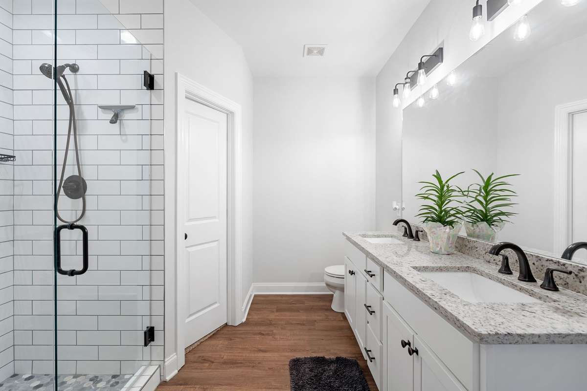 Primary suite bathroom also features double vanities, 2 walk in closets (door to the left is 1 of the 2), granite countertops, and vanity lighting.