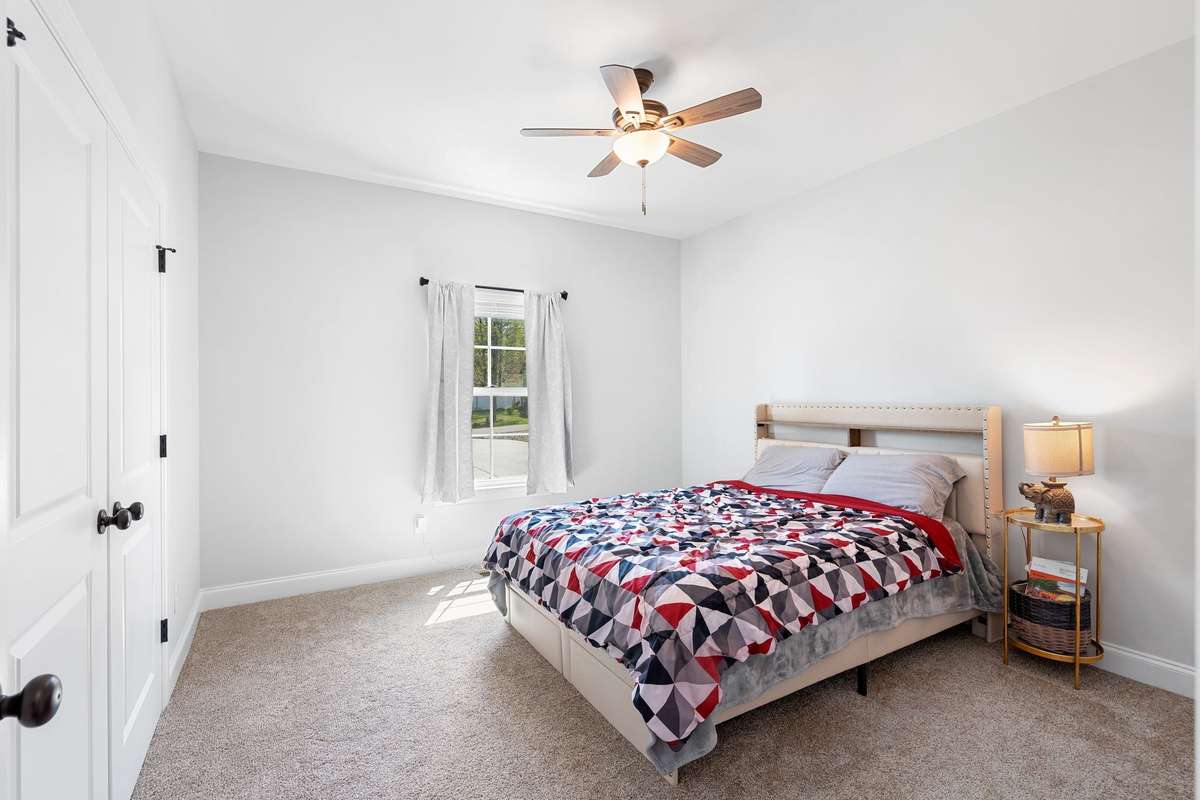 2nd Bedroom at the front of the house facing the driveway. This room features double door deep closet and ceiling fan. Queen sized bed in photo.