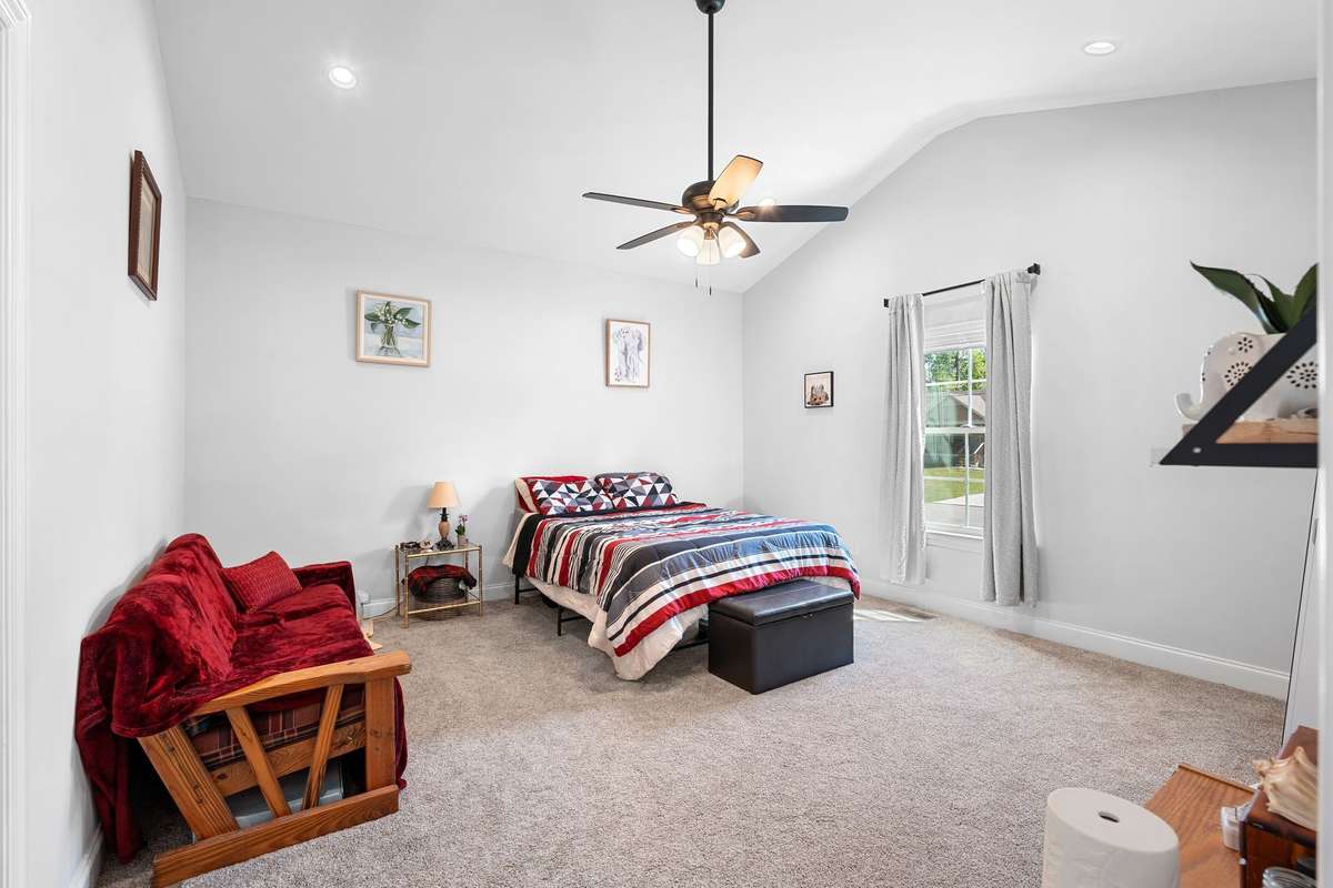 Primary suite features 11 foot vaulted ceilings, tall window, and ceiling fan. Bedrooms only room with carpet.