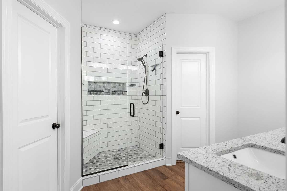 Primary suite bathroom features recently renovated shower with fully tiled shower, bench, toiletry inset, glass door frame, and mirrors also added to both bathrooms. $8k update.
