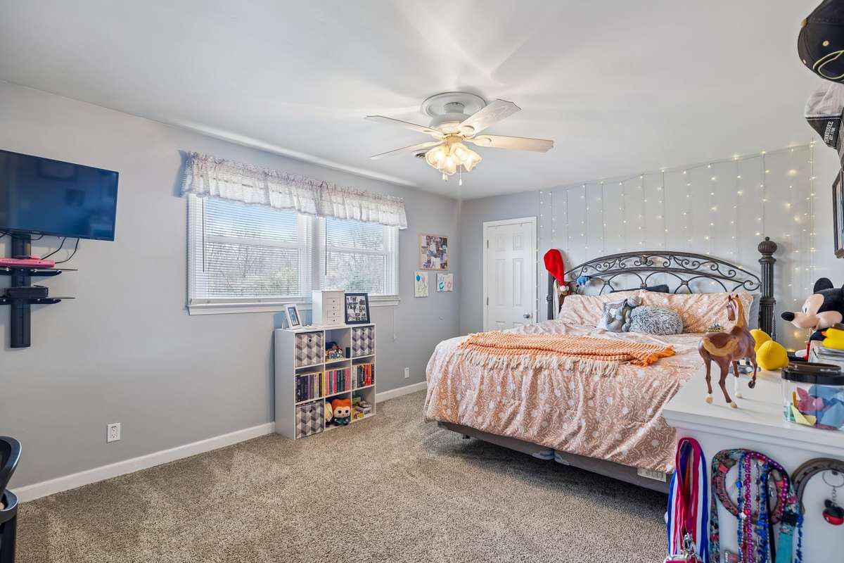 This bedroom feels like a retreat with fairy lights creating a cozy ambiance and plenty of floor space for activities beyond just sleeping.