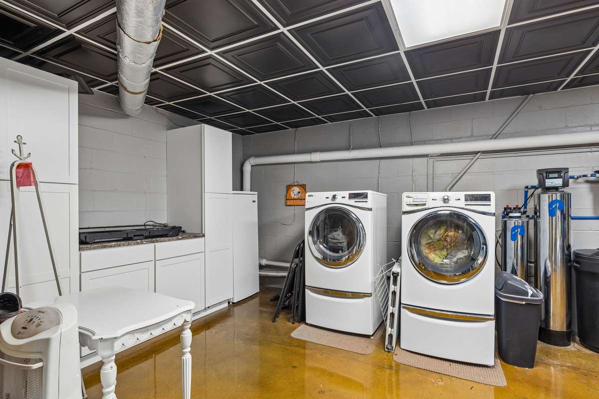 Basement laundry with side-by-side front-loading washer and dryer plus built-in counter space for folding and sorting.