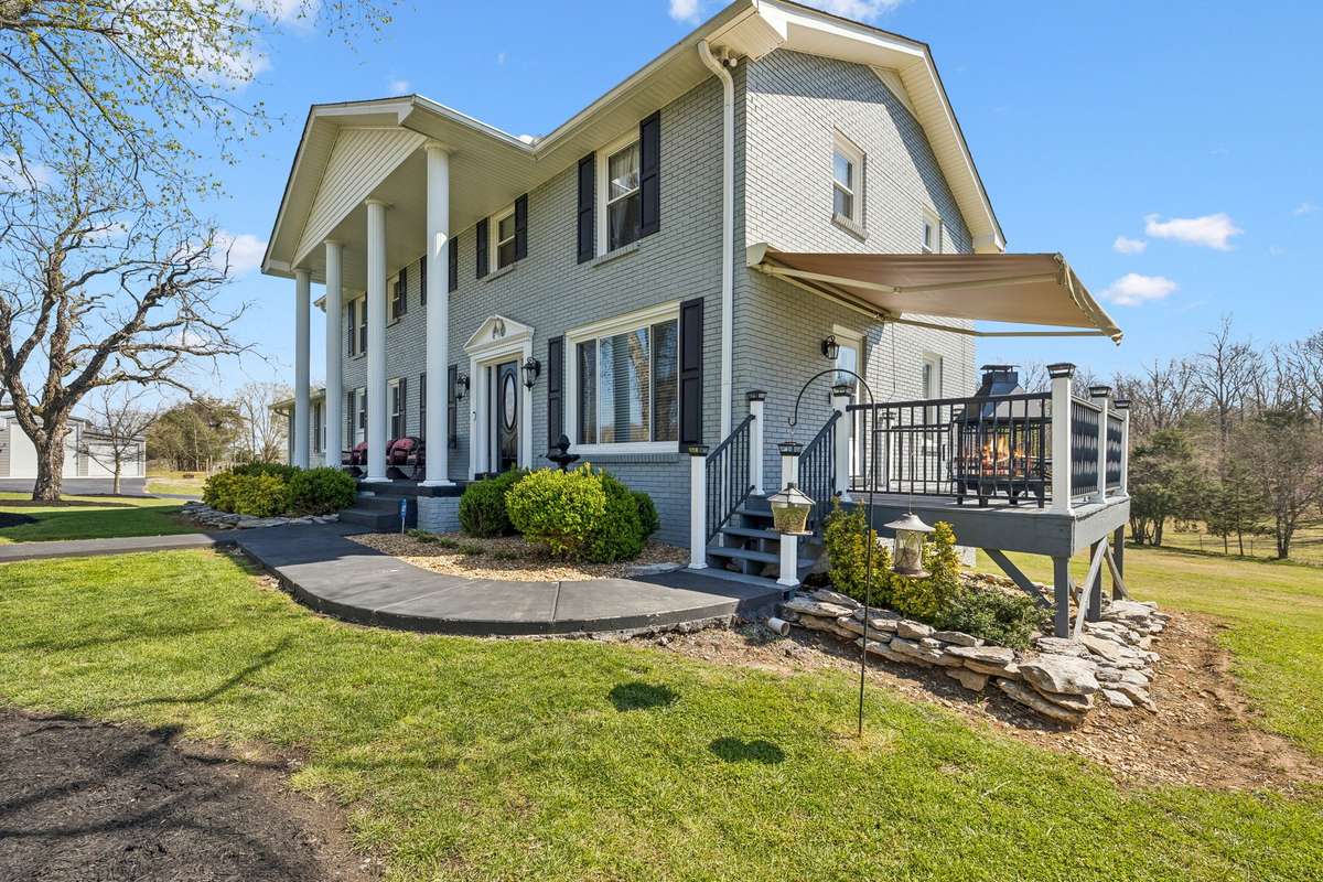 Columned front porch with stone accents and mature landscaping frames the entry to this Christiana colonial.