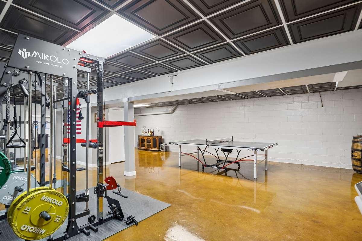Basement fitness area with commercial-grade equipment setup and ping pong table creates a dedicated workout and recreation zone.