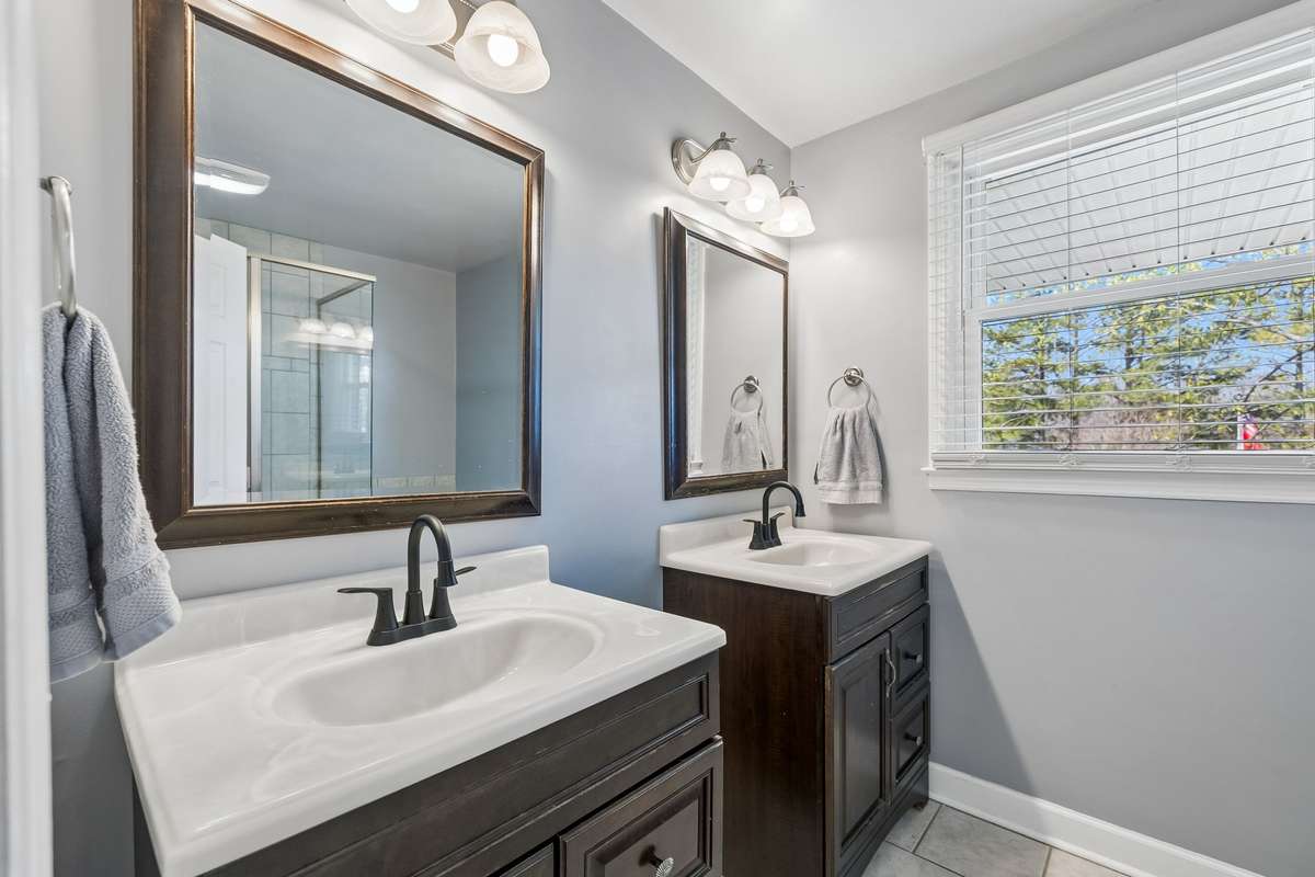 Dark wood vanities with white countertops and matching mirrors create a clean, coordinated look that feels polished without being fussy.