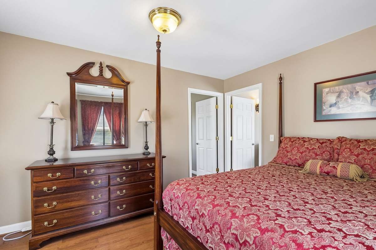 Traditional four-poster bed anchors this bedroom with matching dresser and mirror that complement the warm wood finishes throughout.