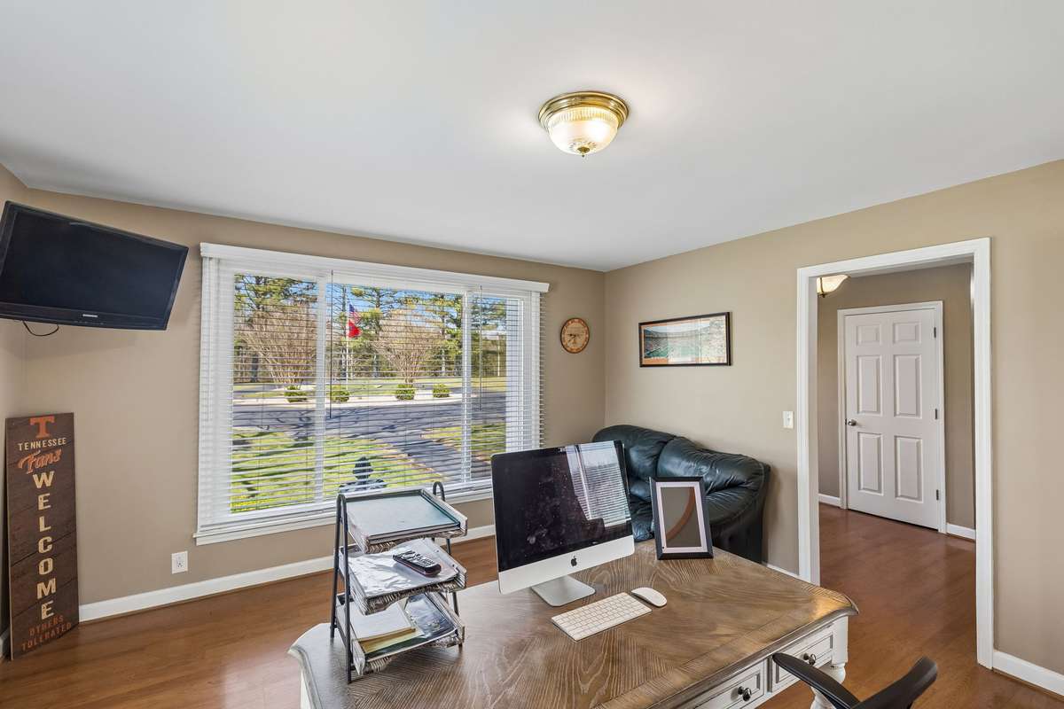 Private office with a built-in desk setup and natural light from the front window creates a productive workspace away from the main living areas.