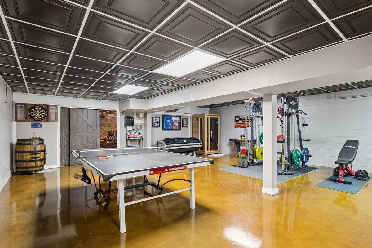 This finished recreation room combines fitness equipment on one side with ping pong and entertainment on the other, plus a sauna tucked into the back corner for the complete basement retreat.