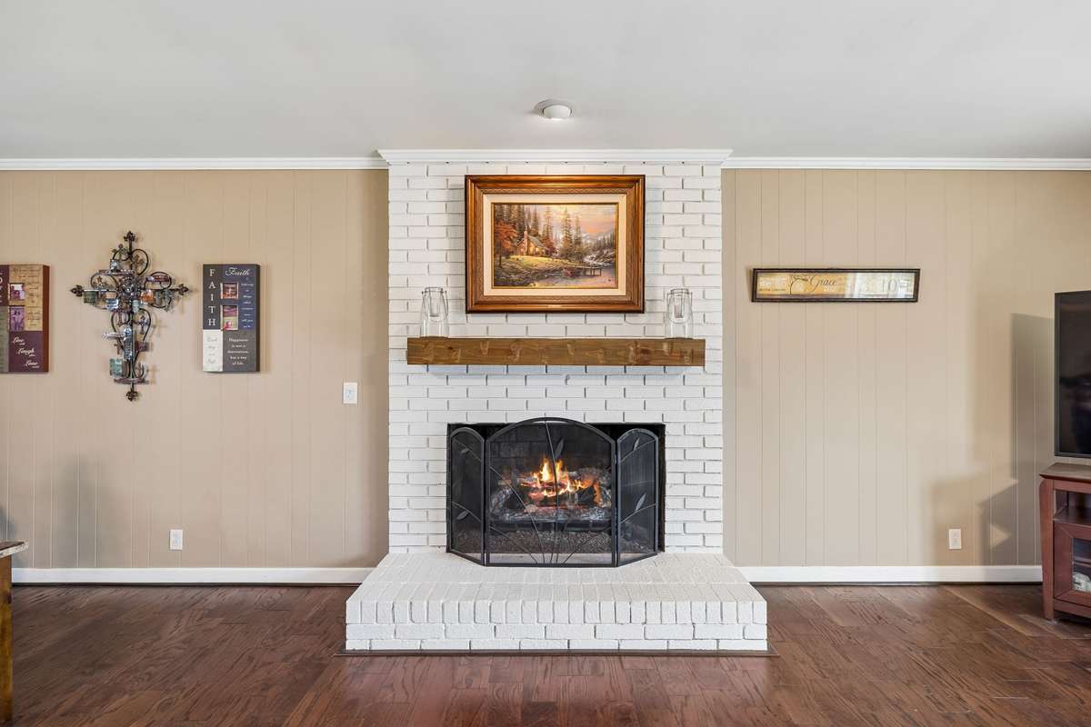Family room with painted brick fireplace and wood mantel creates a comfortable spot to gather while staying connected to the kitchen and dining areas.