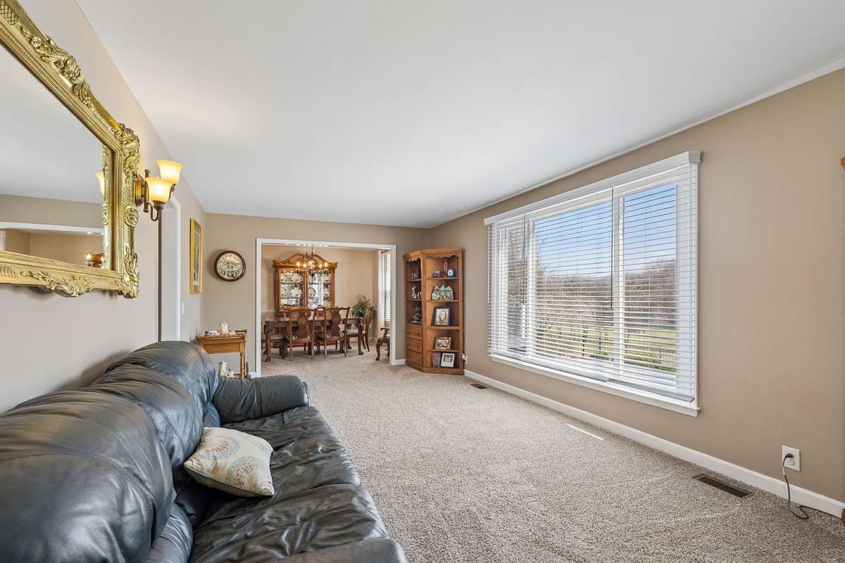Formal living room with neutral walls and carpet connects through to the dining area, creating good flow for hosting.