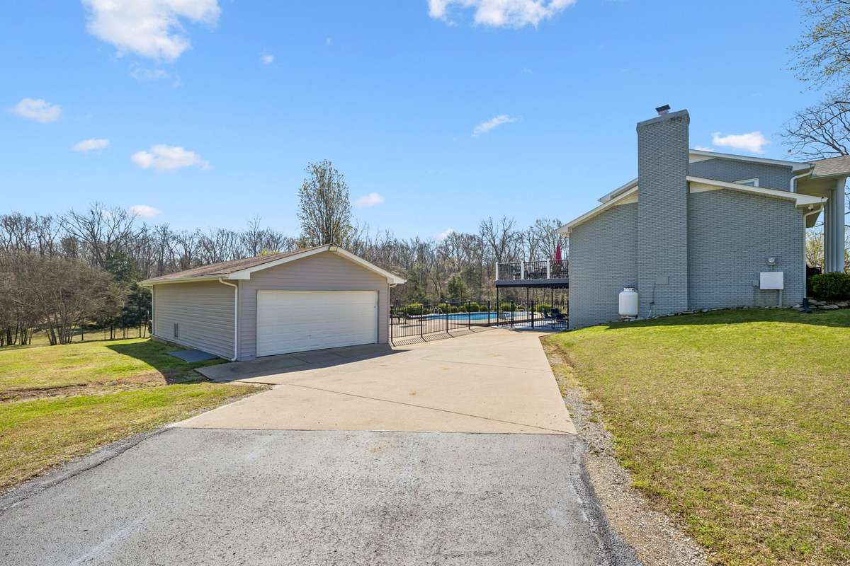 Detached two-car garage and workshop building sit beyond the fenced pool area with easy access from the main driveway.