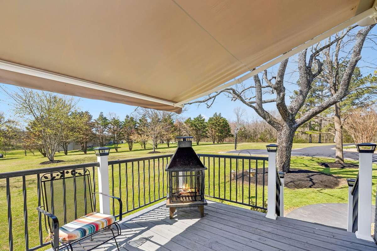 Covered deck with retractable awning creates shade for relaxing while the outdoor fireplace extends the season into cooler evenings.