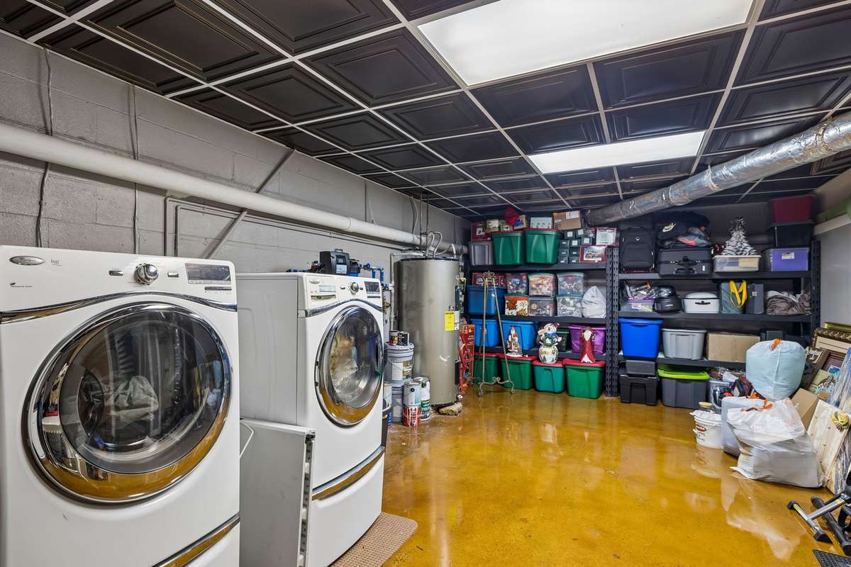Concrete floors and organized storage shelving make this basement laundry setup practical for handling loads while keeping supplies within reach.