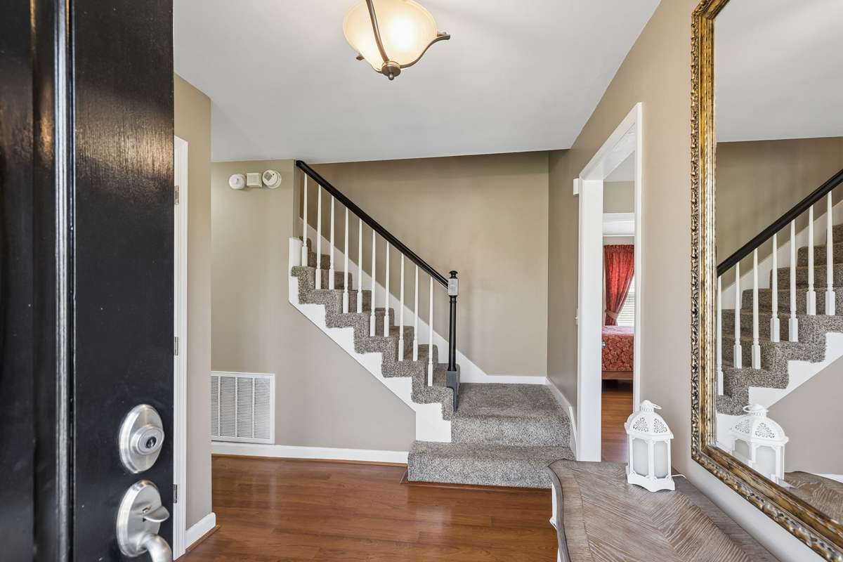 The staircase with gray carpeted treads and white spindles creates an elegant focal point as you step through the front door.