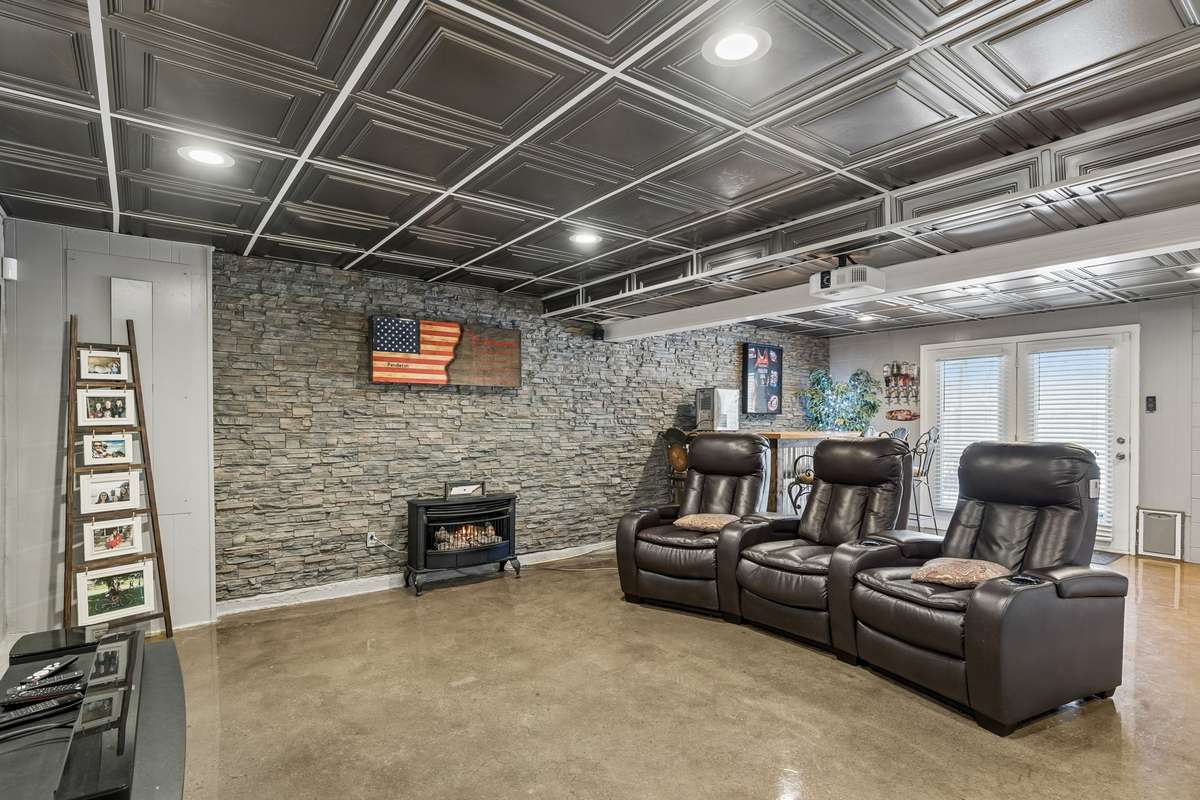 Three leather recliners line up theater-style facing the stone fireplace wall, creating a dedicated spot to settle in for movie nights or watching the game.