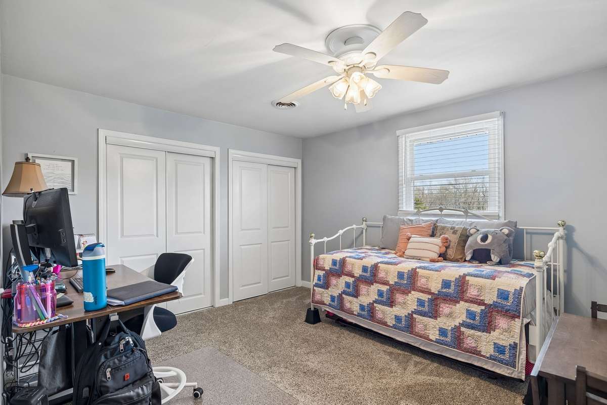 Third-level bedroom with built-in desk space along the wall and dual closets for keeping work and clothes organized.