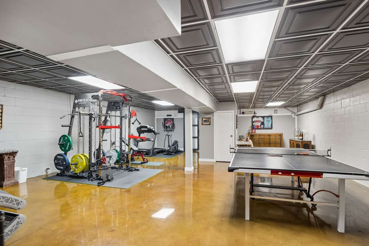 Multi-purpose basement combines workout zone with game area plus built-in storage keeping everything organized and out of the way.