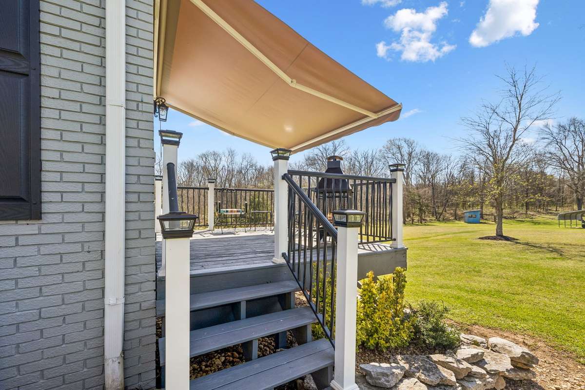 Retractable awning stretches across the deck to cut the sun while still keeping the view of the wooded acreage.