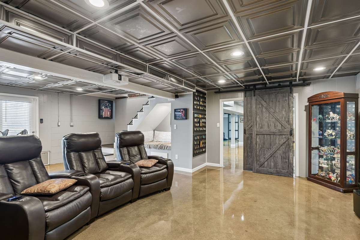 Coffered ceiling treatment adds architectural detail overhead while the polished concrete floors reflect light throughout this lower level entertainment space.