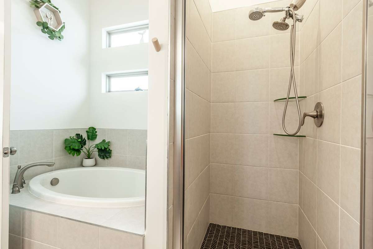 This primary bathroom also boasts a large bathtub and tiled walk-in shower!