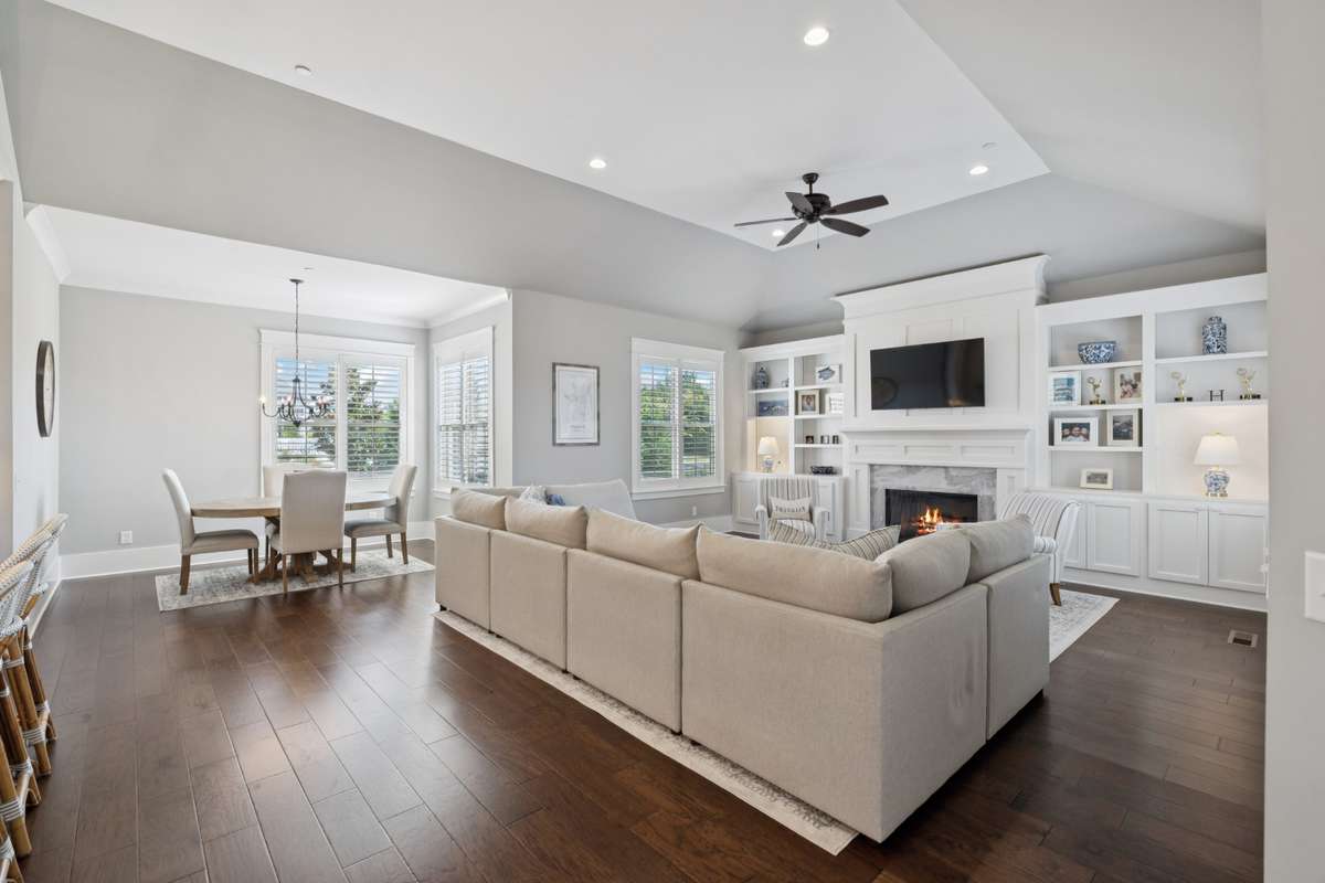 The main living area is filled with natural light and anchored by a stunning marble fireplace, complemented by floor-to-ceiling built-ins that add both character and function.