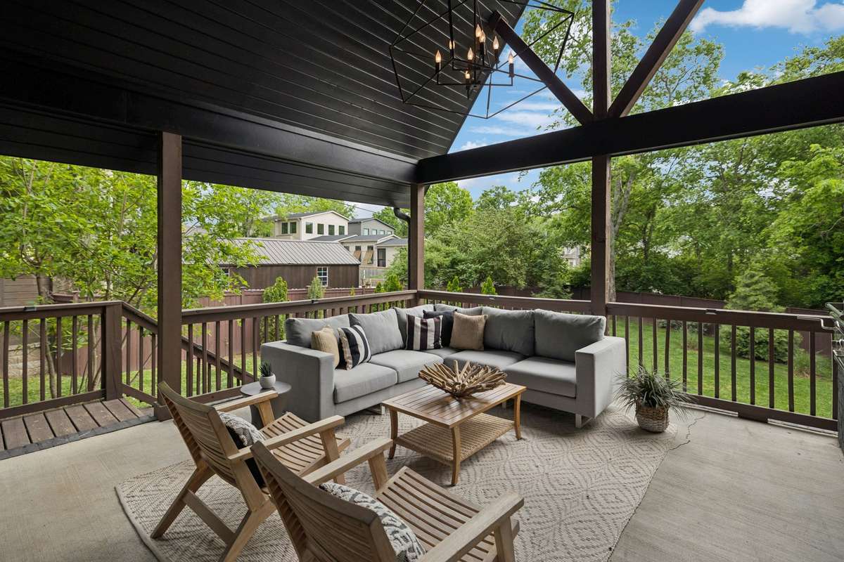 Inviting covered deck designed for entertaining, complete with outdoor kitchen, beverage fridge, and mounted TV