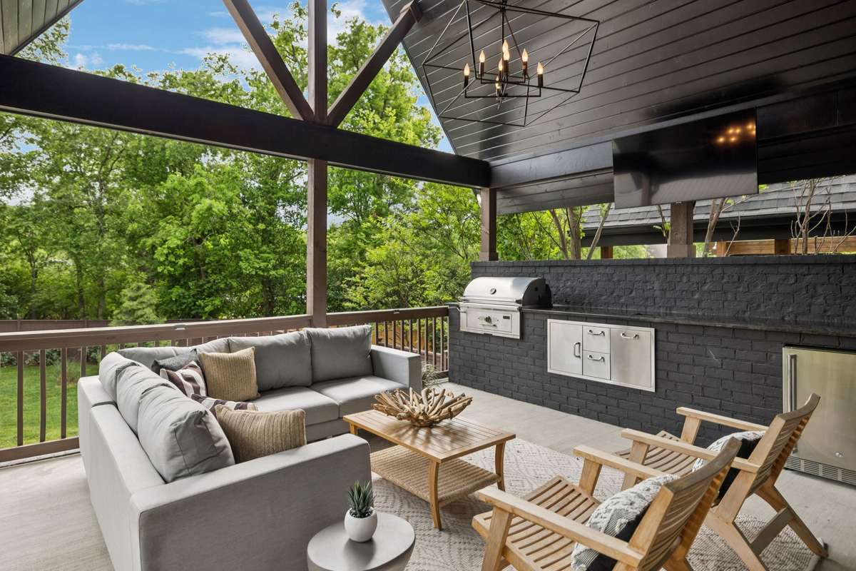 Inviting covered deck designed for entertaining, complete with outdoor kitchen, beverage fridge, and mounted TV