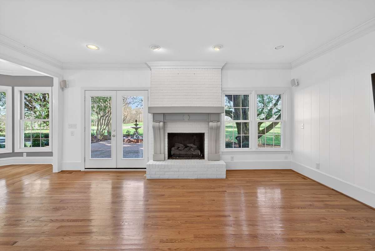 Rich in character, the den showcases a beautifully detailed fireplace, built-in bookcases, and French doors that open to serene patio and fountain views.
