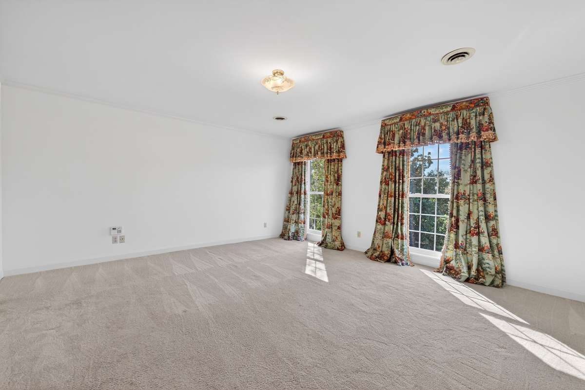 A serene primary retreat with a spa-inspired ensuite bath showcasing marble countertops, heated floors, high-end fixtures, and an expansive walk-in shower.