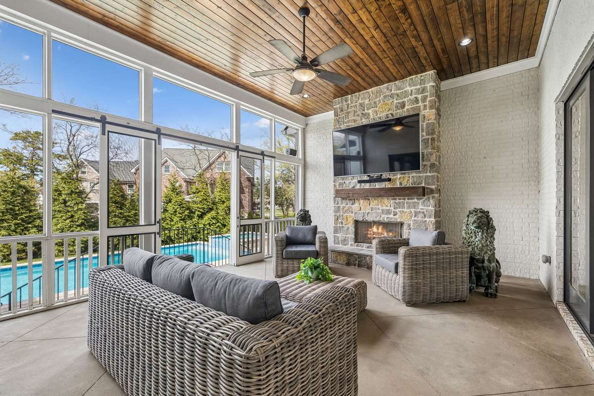 The living room flows seamlessly to the covered, screened-in porch—complete with its own gas fireplace—creating a perfect indoor-outdoor living experience.