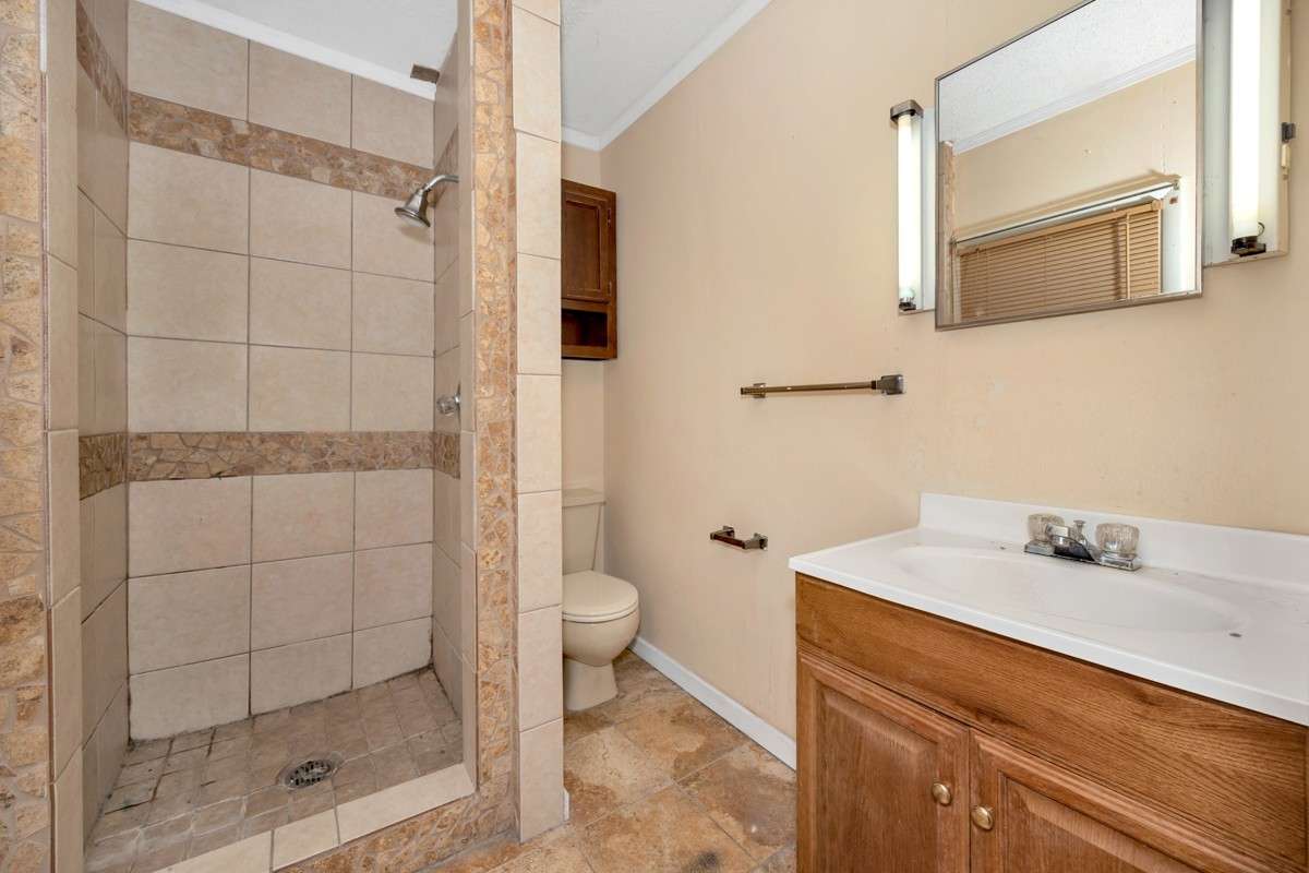 3/4 bathroom- tile flooring, tile shower, crown molding