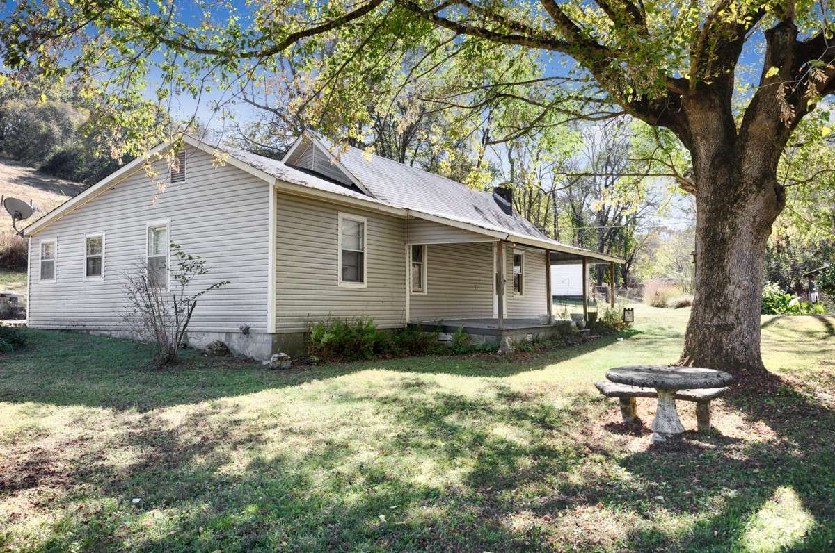 Front of house- covered front porch with home entry, large yard with mature trees for shade