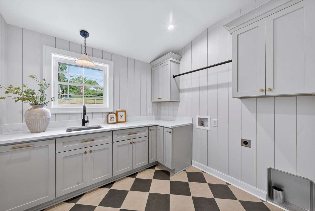 Laundry feels less like a chore in this space with its vertical shiplap, tile floor, lighting and cabinetry.