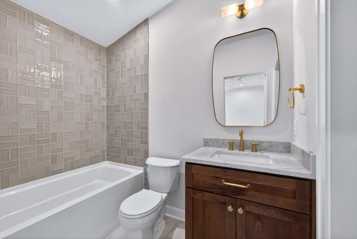 Spacious bathroom with walnut cabinetry and beautiful tile.